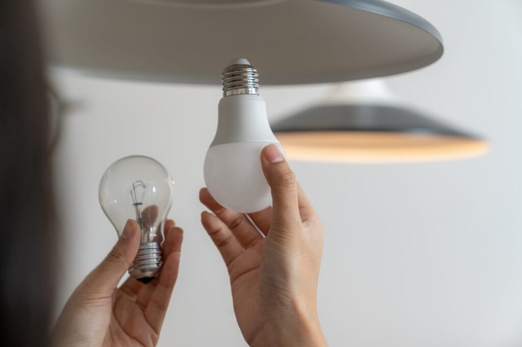 Schimbă becurile clasice cu LED – Economisește energie și bani! Persoană schimbând un bec incandescent cu unul LED pentru eficiență energetică.