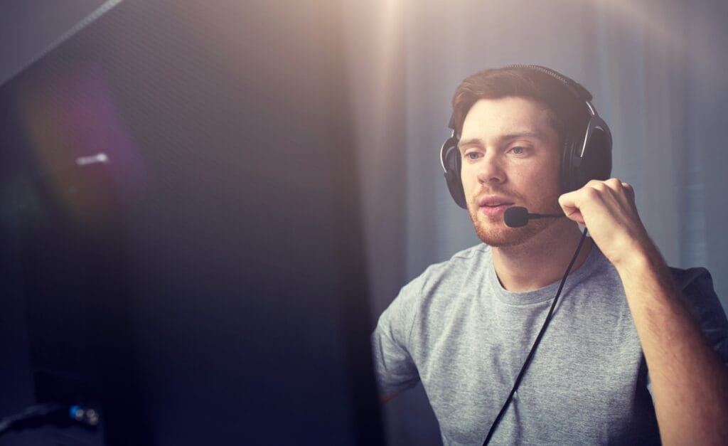 Cum să alegi un headset confortabil pentru sesiuni lungi de gaming Gamer purtând căști ergonomice cu microfon, concentrat în fața monitorului în timpul unei sesiuni lungi.