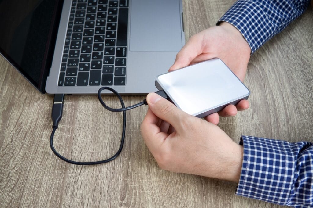 Cum conectezi și protejezi un hard disk extern Bărbat conectează un hard disk extern la un laptop, exemplu de utilizare corectă pentru prelungirea duratei de viață