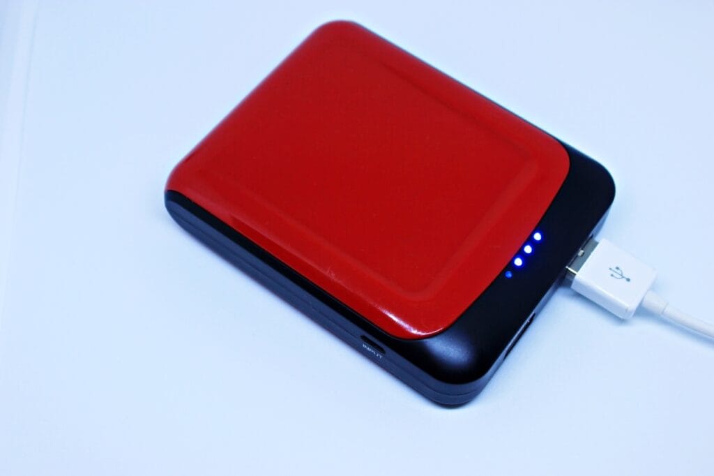 Cum interpretezi indicatorii LED ai bateriei externe? Baterie externă roșie cu indicatori LED activi, conectată la un cablu USB.