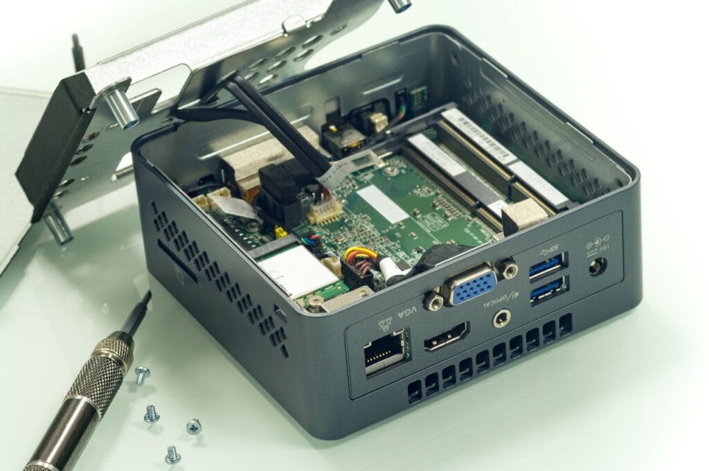 Upgrade hardware pentru Mini PC – interior accesibil și modular Mini PC deschis pe birou, cu șurubelniță și componente vizibile, pregătit pentru upgrade de RAM și SSD.