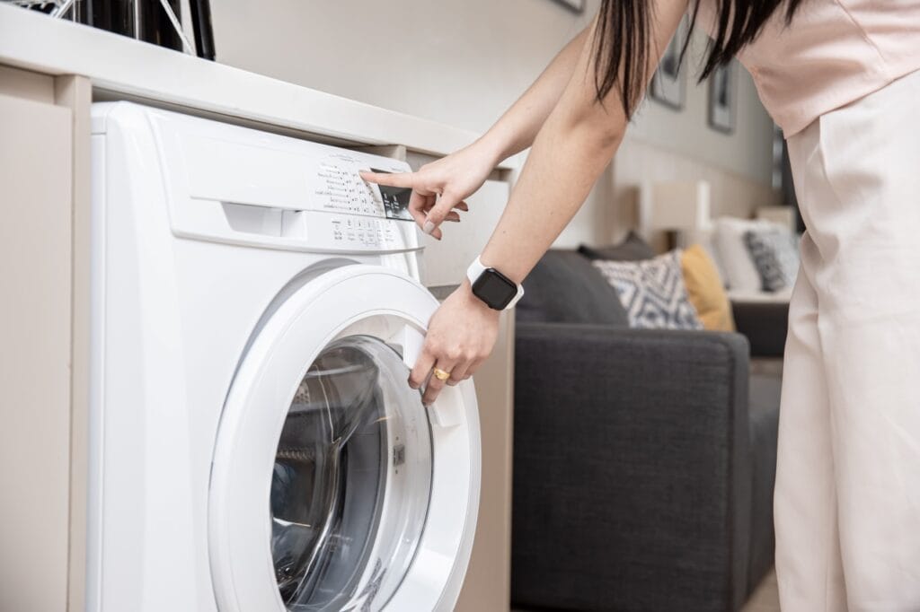 Cum să alegi programul potrivit la mașina de spălat – Ghid pentru eficiență maximă Femeie setând un program pe mașina de spălat – ghid pentru alegerea corectă a ciclului de spălare.