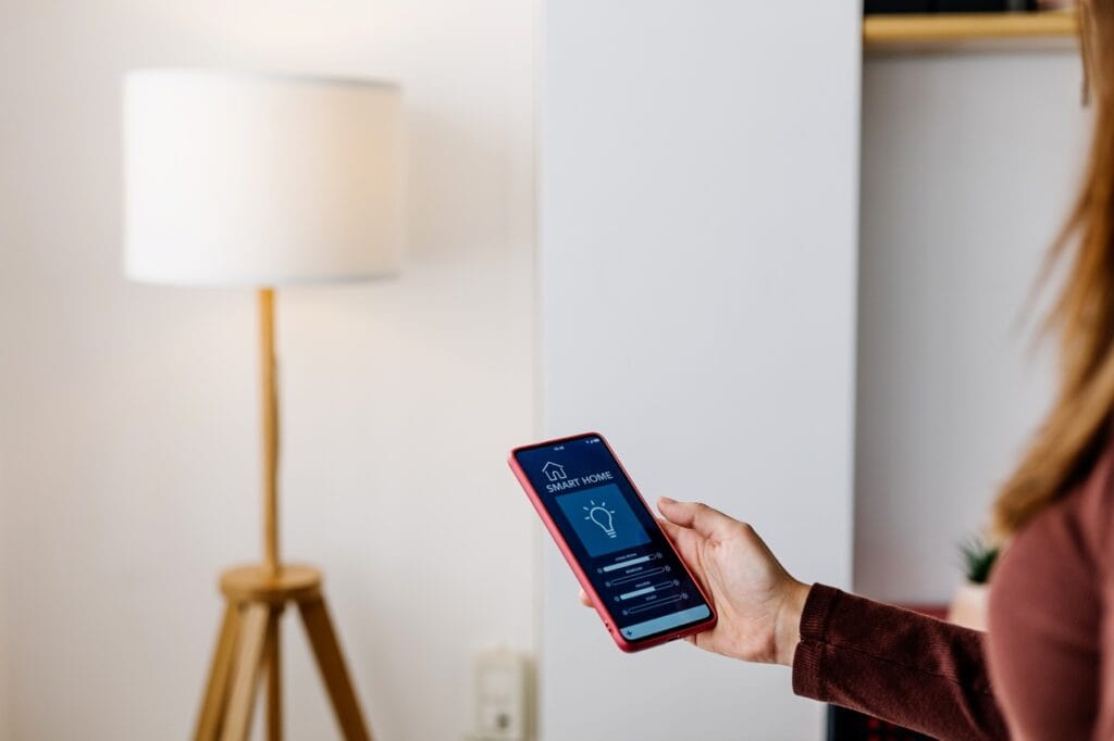 Control inteligent al iluminatului de interior cu smartphone-ul Persoană utilizând o aplicație smart home pe telefon pentru a controla lumina unei lămpi de interior. Tehnologie de iluminat inteligent, controlată prin smartphone.