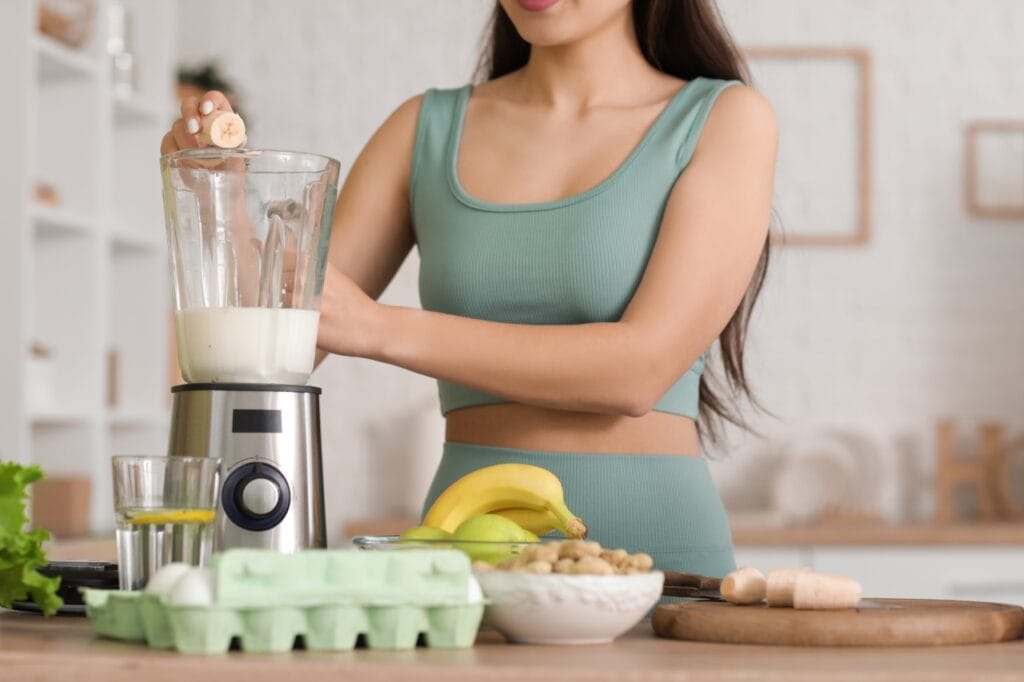 Ce să mănânci înainte și după cycling indoor Alimentație sănătoasă înainte de antrenament – banană, lapte, ouă și alimente naturale pe un blat de bucătărie.