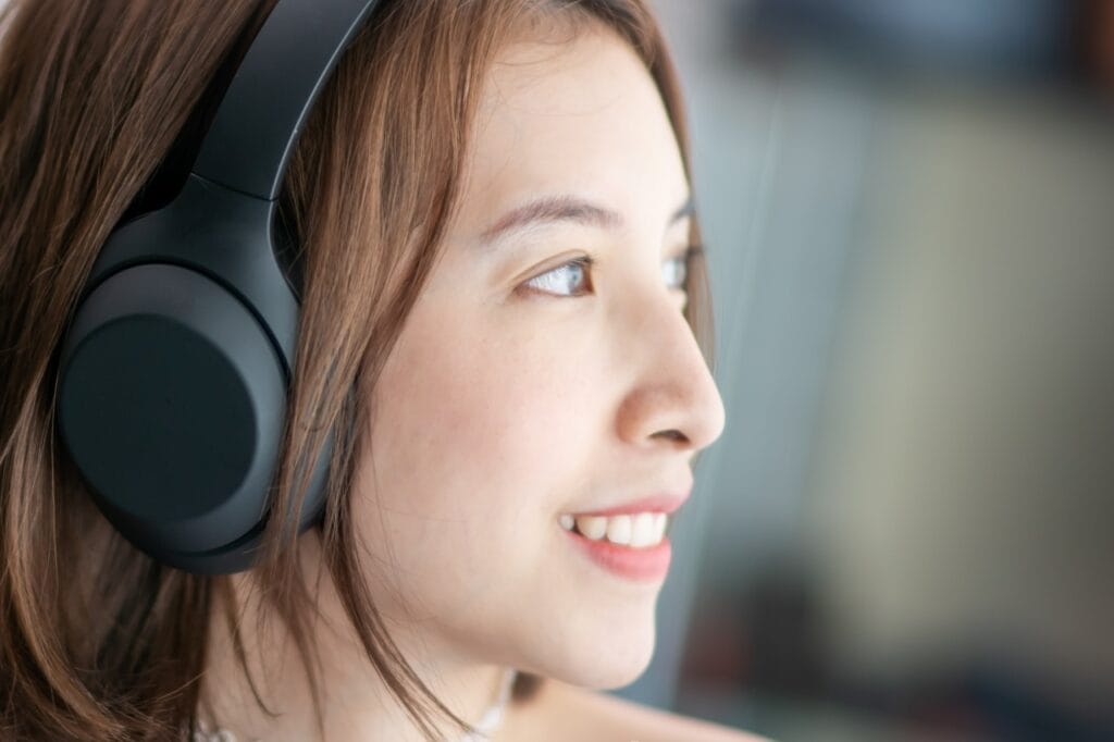Experiența sunetului echilibrat cu căști over-ear premium Femeie purtând căști over-ear wireless de înaltă calitate, ascultând muzică cu sunet echilibrat