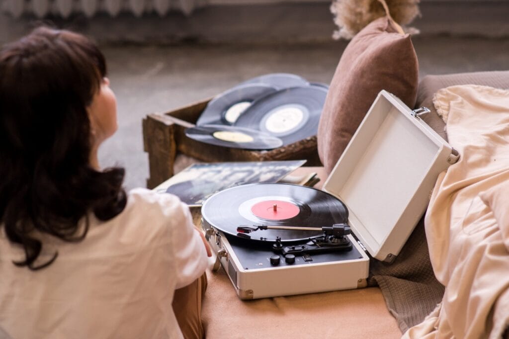 Imagine cu o femeie ascultând vinil pe un pick-up modern, într-un living relaxant, simbolizând avantajele unui phono preamp integrat