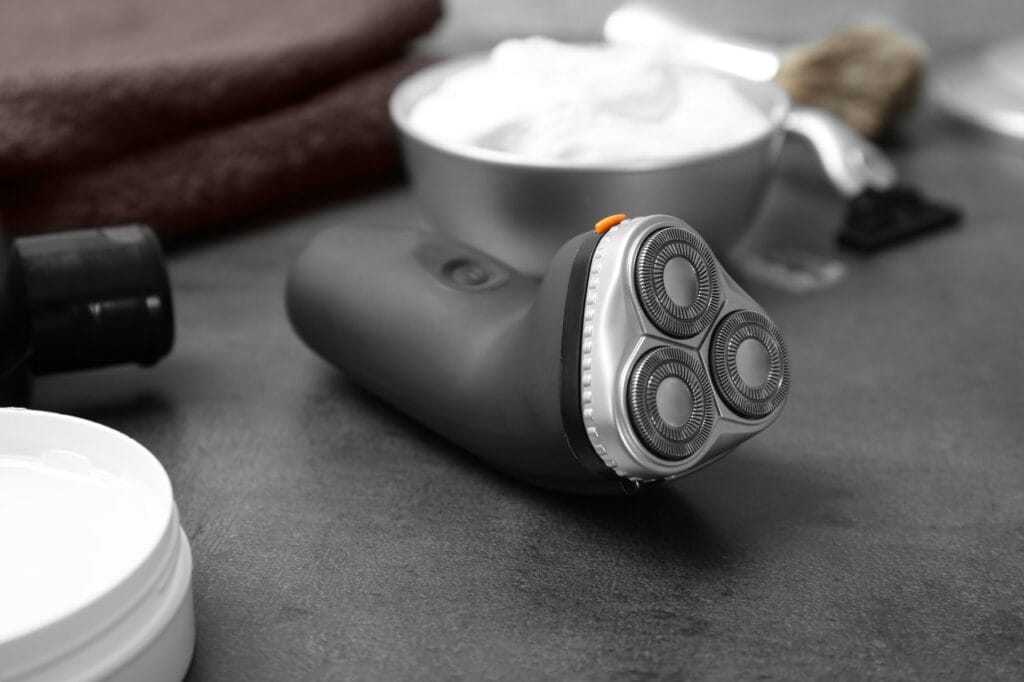 Ergonomie în bărbierit: diferența dintre un aparat obișnuit și unul performant Aparat de ras electric cu design ergonomic pe blat de baie, lângă produse de bărbierit