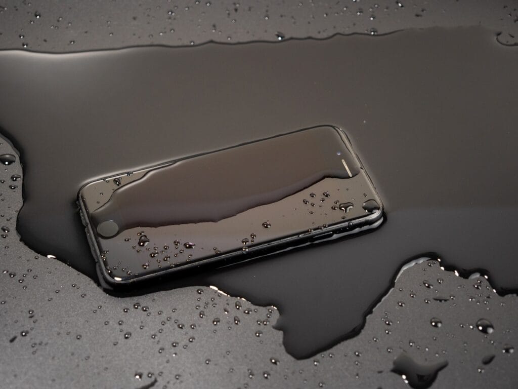 Ce trebuie să știi despre folie și impermeabilitatea telefonului tău Telefon smartphone ud pe o suprafață neagră, expus la apă