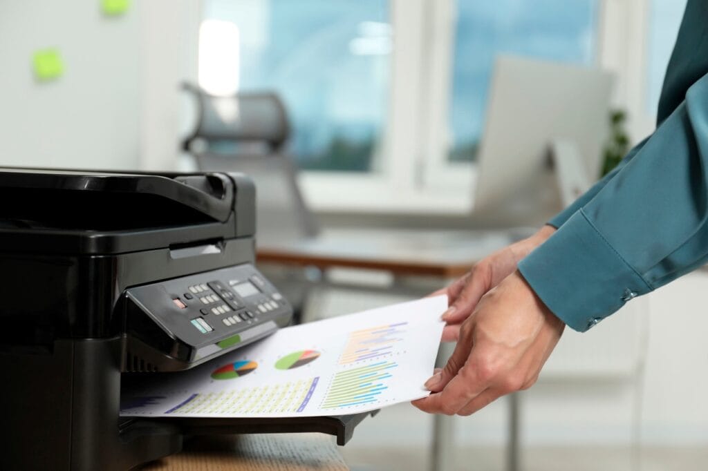Rezoluția imprimantei: cheia clarității în printuri color și text Persoană care scoate un document color imprimat cu grafice și diagrame la o imprimantă multifuncțională