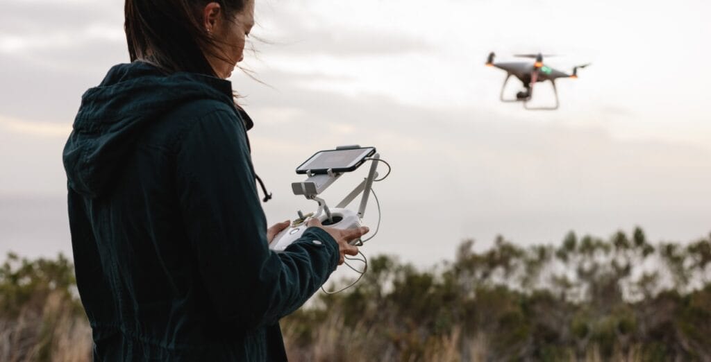 Calibrarea dronei: primul pas spre un zbor sigur și stabil Persoană calibrând o dronă cu telecomandă și ecran, pe fundal natural