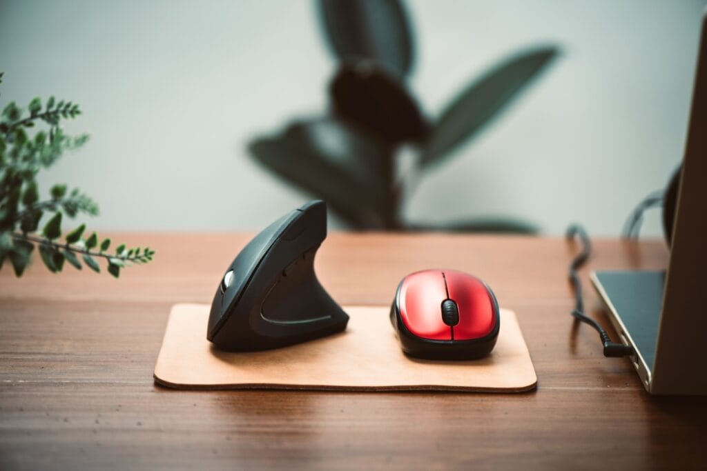 Comparare mouse vertical ergonomic cu mouse tradițional pe birou din lemn