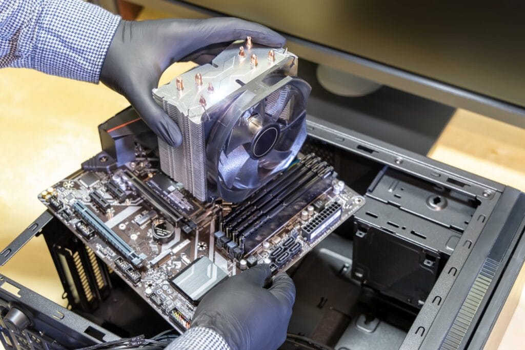 Calitatea componentelor: Fundamentul unei plăci de bază durabile Tehnician instalează cooler pe placă de bază, importanța VRM-ului și calitatea componentelor pentru durabilitate PC