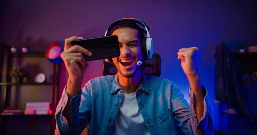 Gaming intens cu rată de refresh de top Gamer entuziast cu căști și telefon, jucând pe ecran cu refresh ridicat pentru performanță superioară