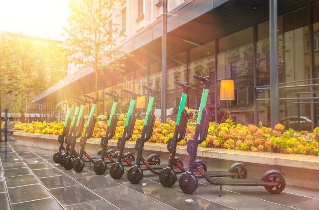 Trotinete electrice verzi aliniate pe o stradă urbană modernă, simbol al mobilității sustenabile în orașe