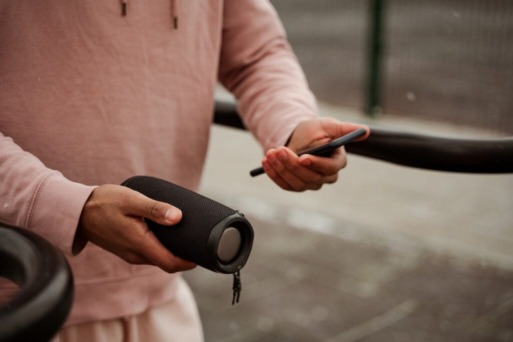 Boxă Bluetooth cu radiator pasiv ținută în mână, conectată la smartphone în aer libe