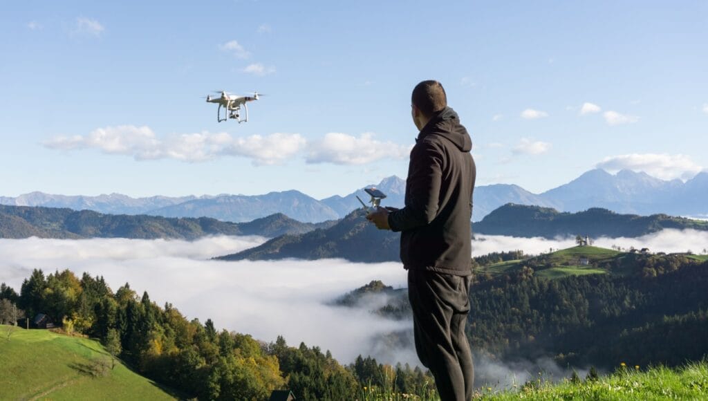 Capturarea perfecțiunii din aer: secretele unei fotografii reușite cu drona Bărbat controlând o dronă deasupra munților, în timpul unei sesiuni de fotografie aeriană la răsărit
