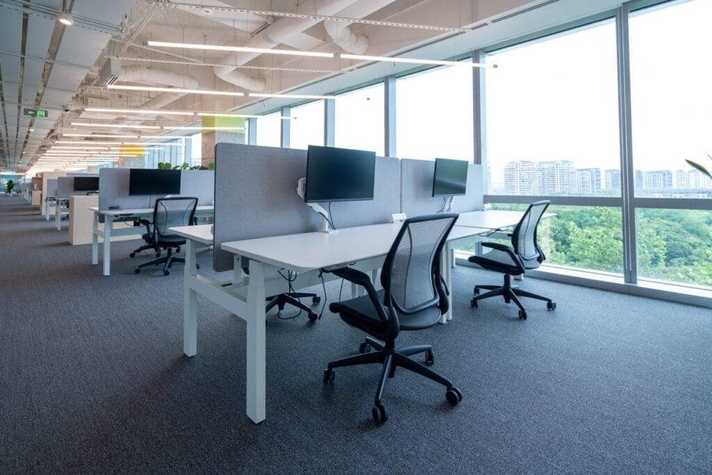 Spațiu de birouri open space cu suporturi reglabile de monitor pentru ergonomie și organizare eficientă