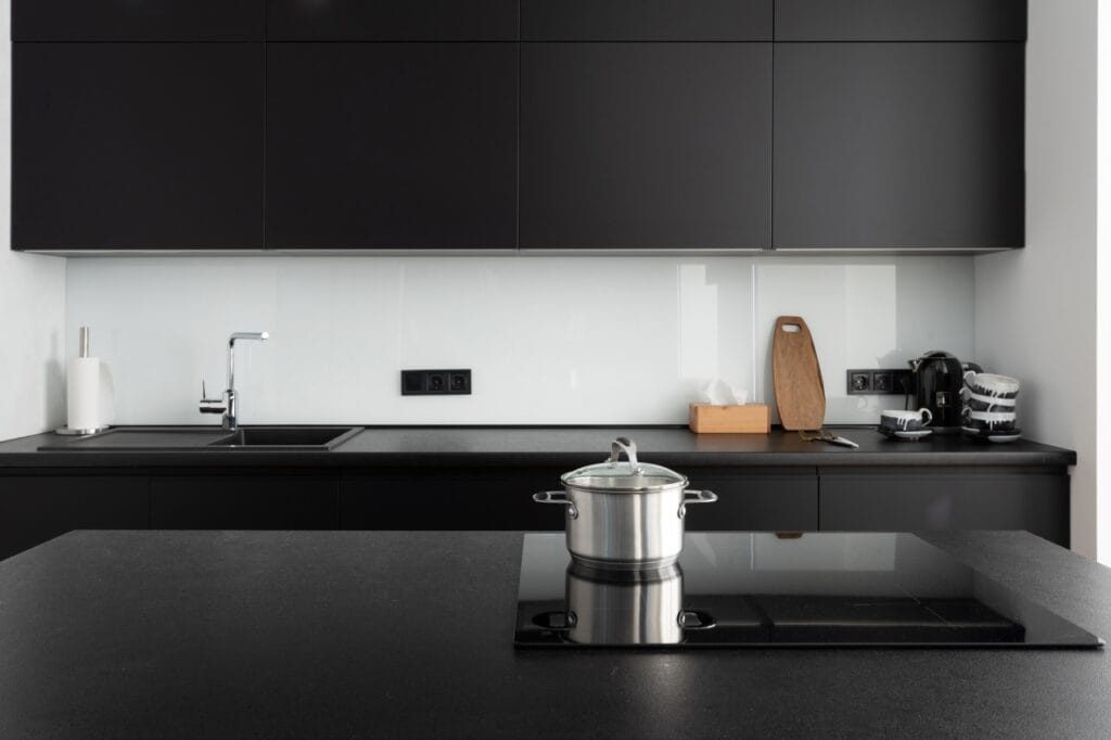 Aspect modern și tehnologie avansată: plita cu inducție în bucătăria perfectă Bucătărie modernă cu plită cu inducție încorporată pe blat negru.