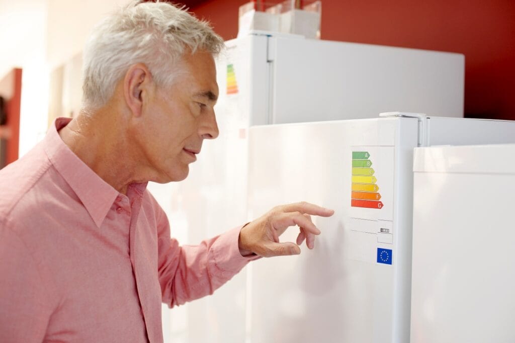 Eticheta energetică spune adevărul – învață să o citești corect Etichetă energetică pe combină frigorifică examinată de cumpărător, comparând consumul real în kWh pentru 2025