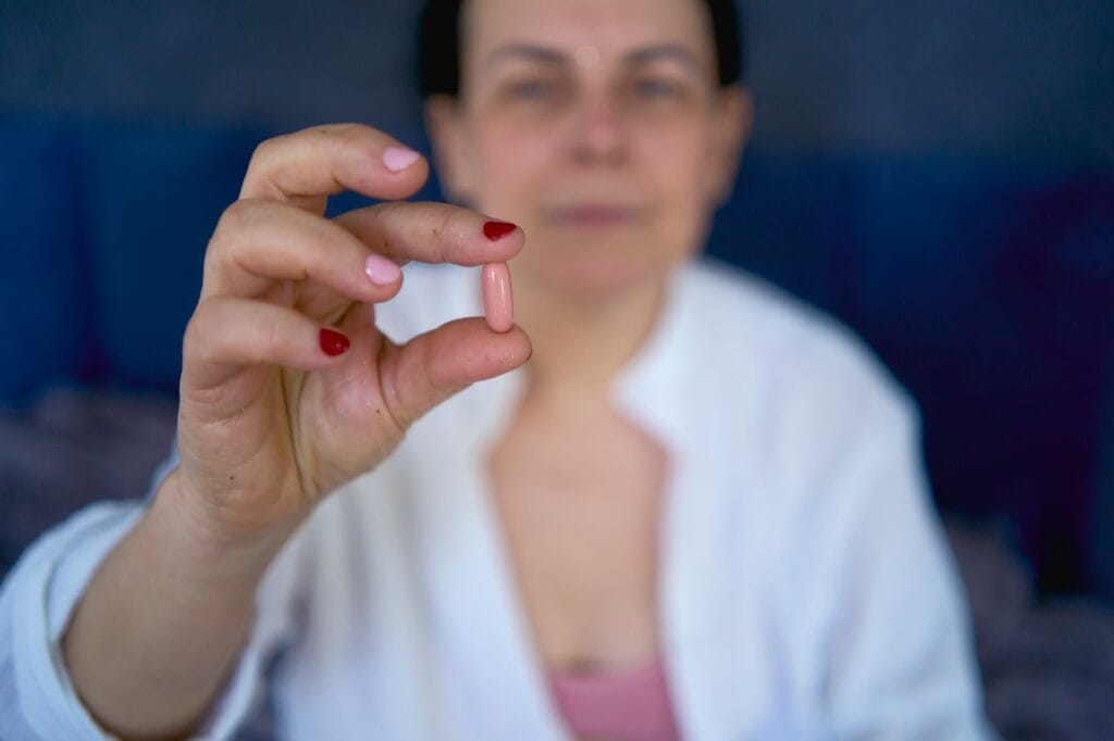 Când ai nevoie de suplimente pentru oase și articulații? Supliment nutritiv pentru oase și articulații ținut de o femeie, utilizat în prevenția problemelor musculo-scheletale.