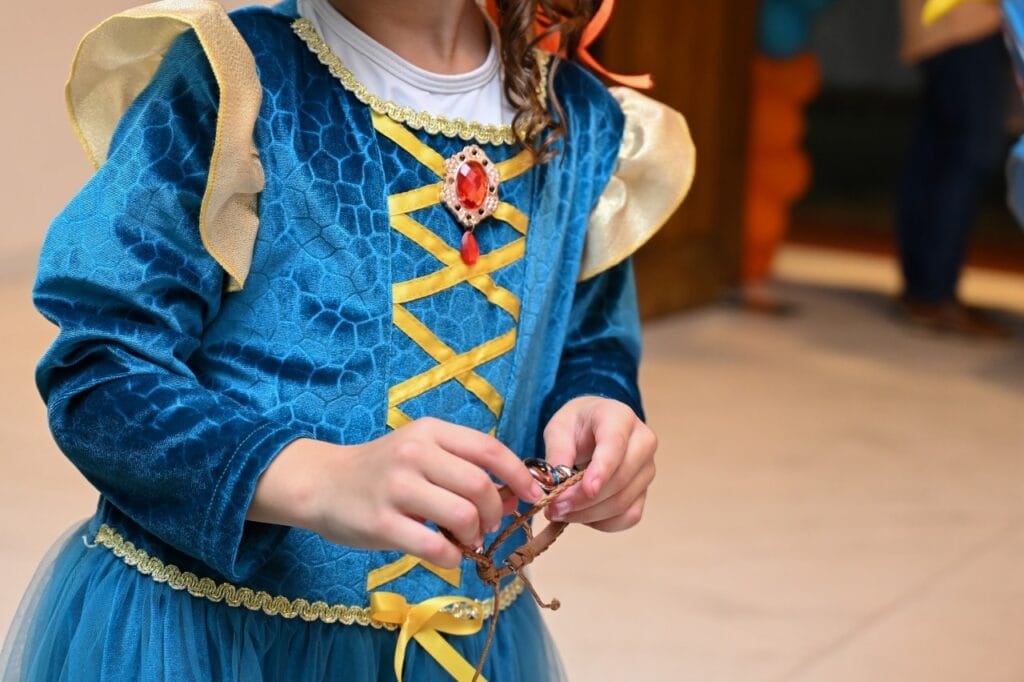 Costumul preferat – cheia către un personaj de vis Detaliu costum carnaval fetiță – rochie de prințesă albastră cu bijuterie roșie, inspirată din desene animate