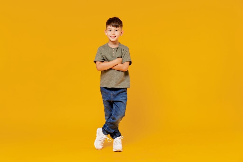 Mai mult decât un tricou: sustenabilitate cu stil Băiat îmbrăcat simplu cu tricou din bumbac și blugi, pe fundal galben, simbolizând moda sustenabilă pentru copii