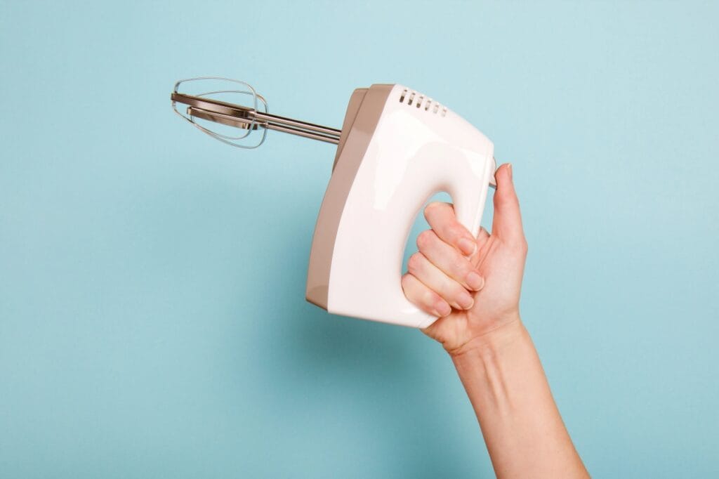 Ergonomie în prim-plan: mixerul care nu obosește mâna Persoană ținând un mixer manual ergonomic, ideal pentru utilizare confortabilă și eficientă în bucătărie
