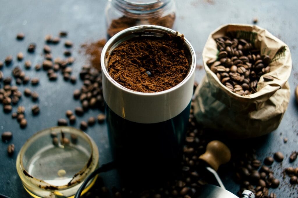 Imagine cu râșniță de cafea și cafea măcinată fin pentru espresso, boabe în pungă și pe masă, detaliu relevant pentru extracție profesională