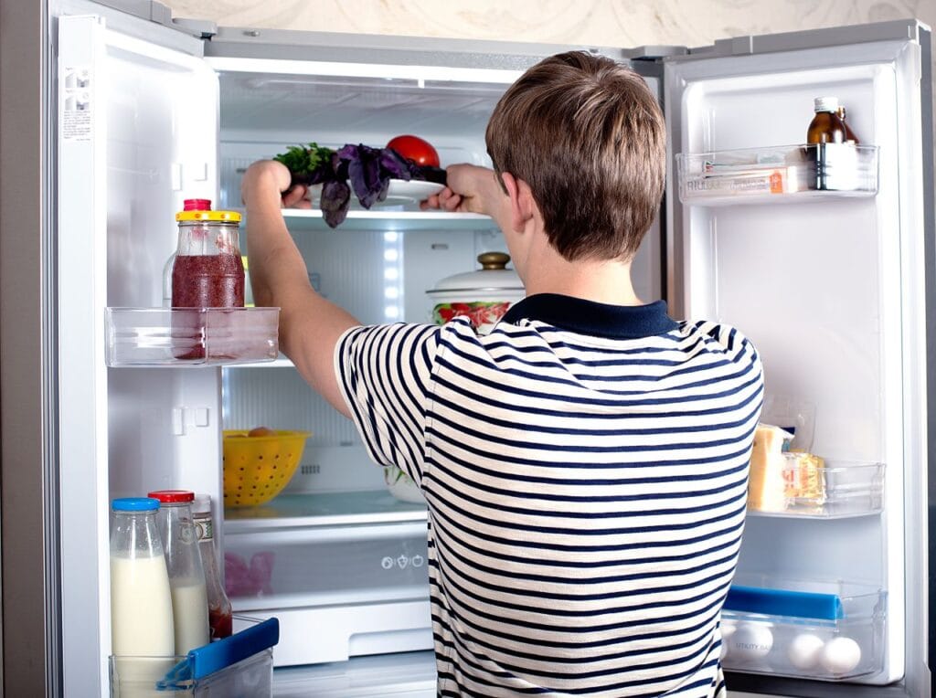 Cum să organizezi corect un frigider Side by Side pentru o familie organizată Persoană care organizează un frigider Side by Side pentru a păstra alimentele în siguranță și ordine