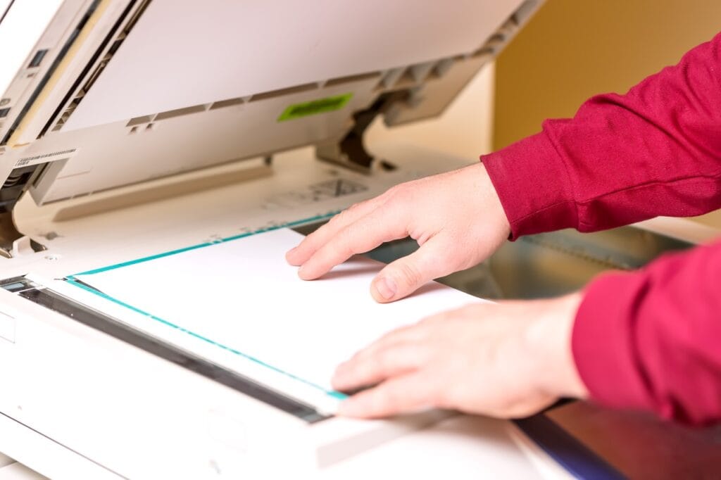 Persoană plasând o foaie pe un scanner dedicat profesional pentru scanare de înaltă calitate