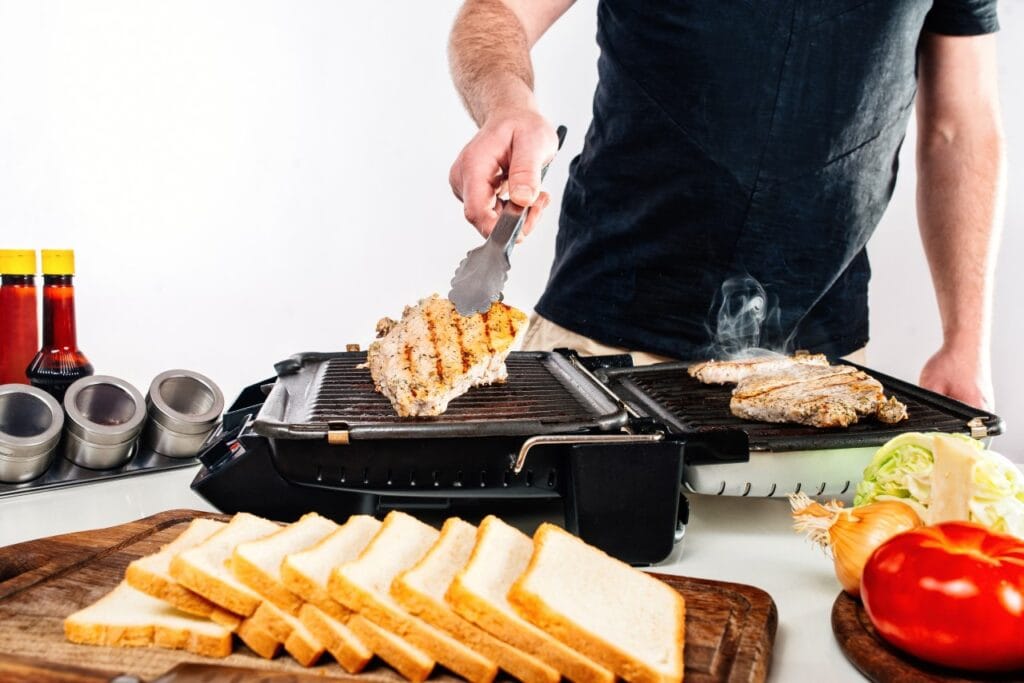 Gătit pe grill electric deschis la 180°, cu carne și legume, bucătărie modernă acasă