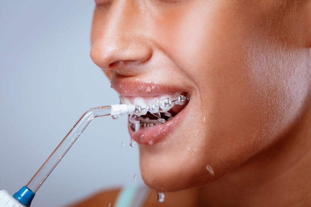 Jet delicat pentru gingii sensibile Persoană cu aparat dentar folosind irigator bucal pentru curățare delicată a dinților și gingiilor sensibile