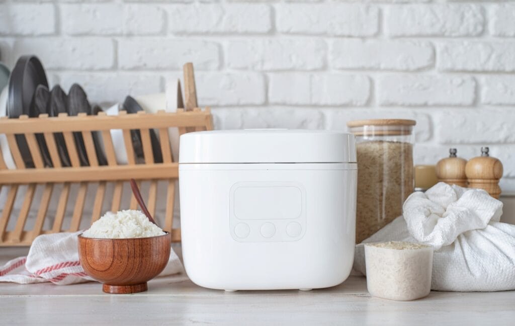 Rice cooker smart alb, cu bol de orez și ingrediente pe blat de bucătărie