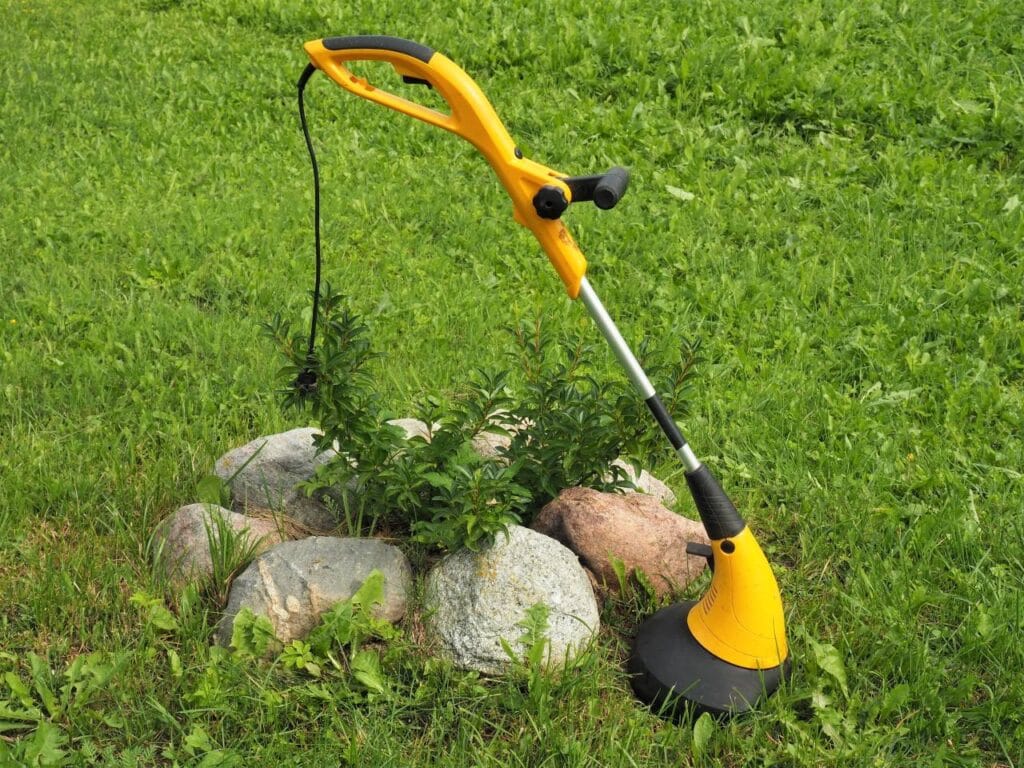 Trimmer electric cu fir galben folosit la tuns gazon și curățarea marginilor grădinii