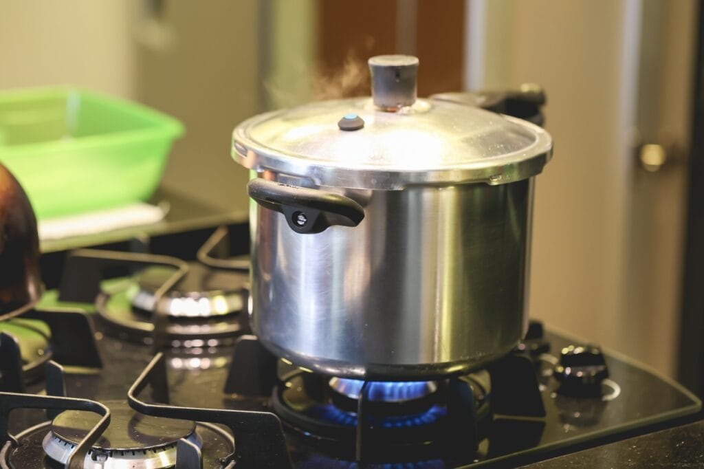 oală sub presiune clasică pe aragaz în timpul fierberii, cu aburi vizibili sub capac