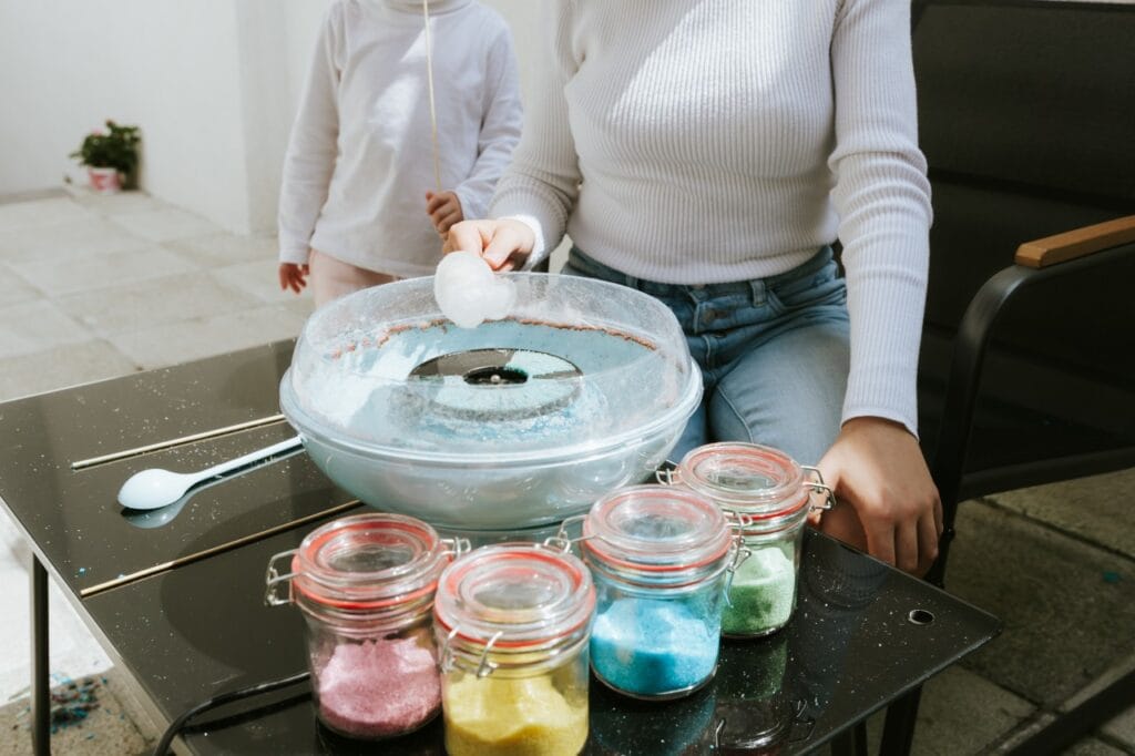 Aparat de vată de zahăr cu zahăr roz, galben, albastru și verde pregătit pentru utilizare acasă.