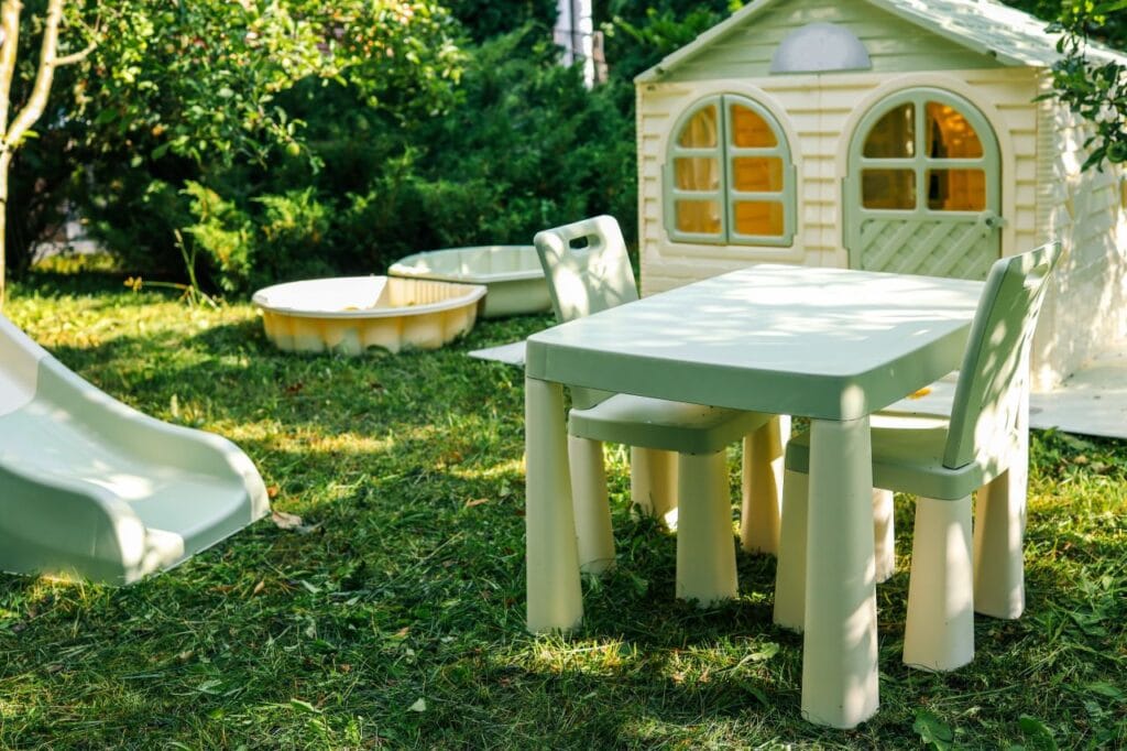 Mobilier și accesorii din plastic lângă o căsuță de joacă în curte