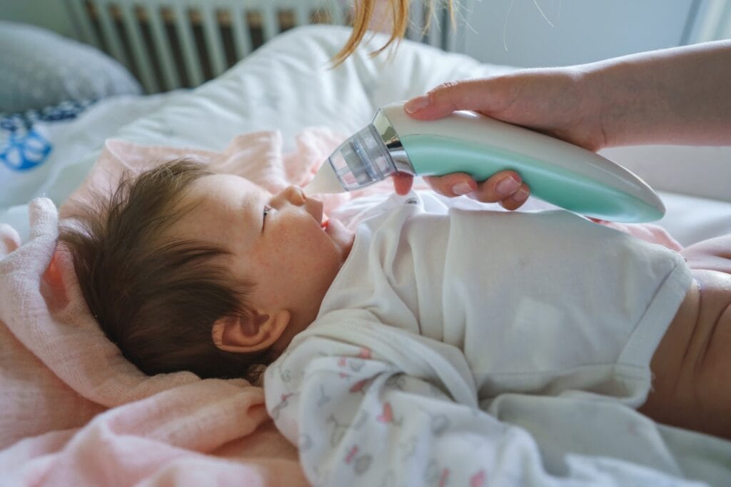 Părinte folosește aspirator nazal pentru copii cu muzică și lumină pentru a calma bebelușul