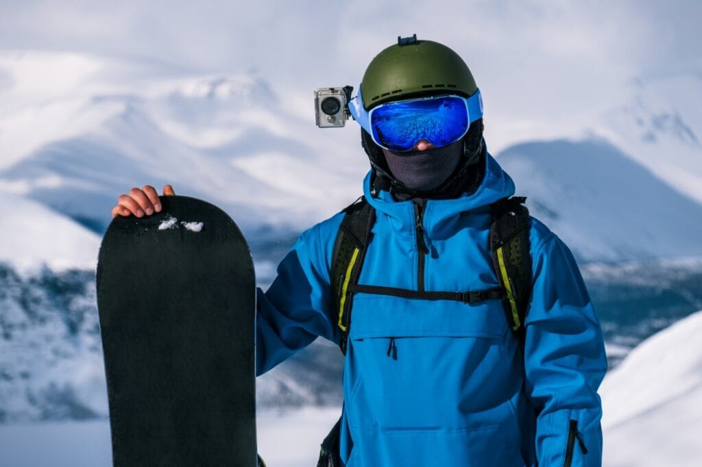 sportiv pe snowboard cu cameră de acțiune pe cască, filmare montană iarna