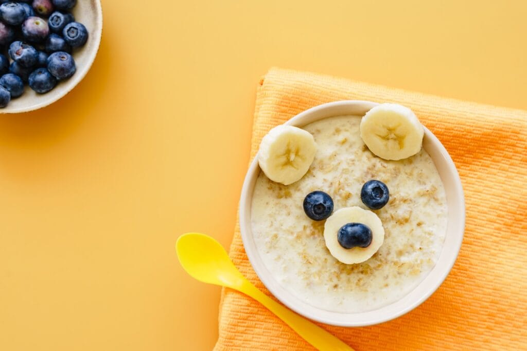 Bol de cereale pentru bebeluși decorat cu felii de banană și afine