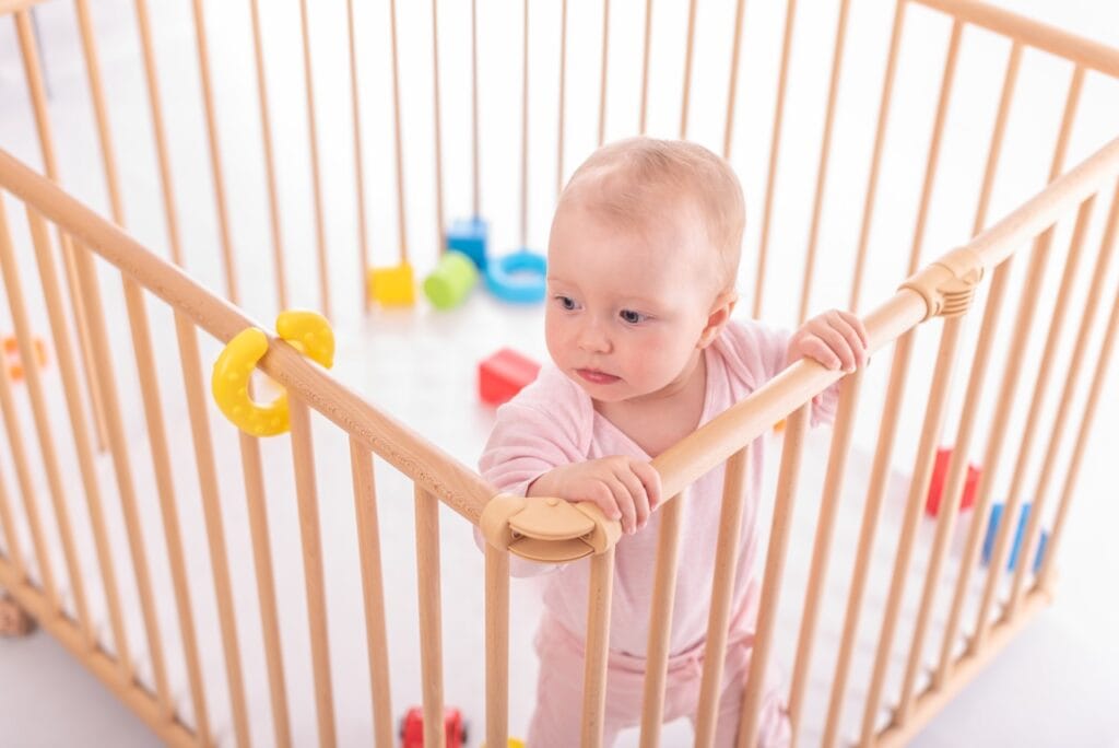 Țarc pătrat cu design aerisit, confort și siguranță într-un singur spațiu Țarc din lemn pătrat cu bebeluș înăuntru, într-un mediu luminos și organizat pentru joacă