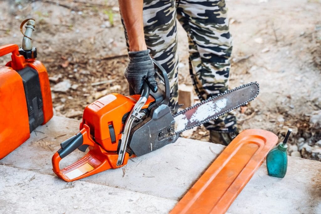 drujbă pe benzină cu lanț tocit, lângă canistră și ulei, pregătită pentru schimbare