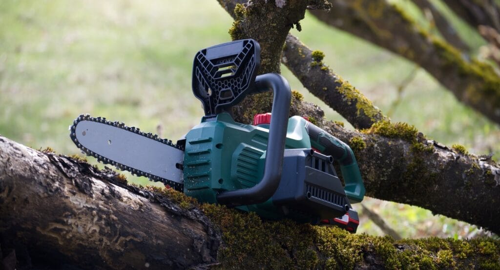 Întreținerea acumulatorului pentru drujba electrică Drujbă electrică cu acumulator, sprijinită pe trunchi de copac, ilustrând importanța întreținerii bateriei