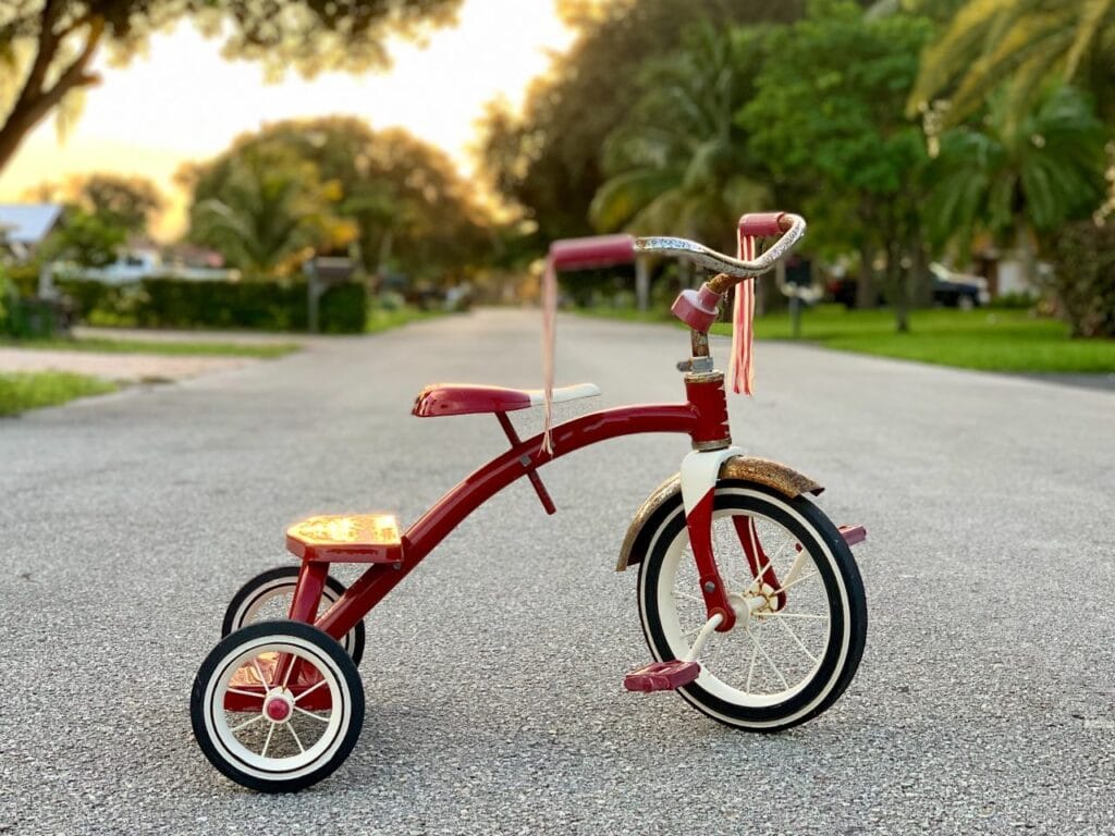 tricicletă roșie pentru copii cu culori vii și design ergonomic vizibil pe stradă