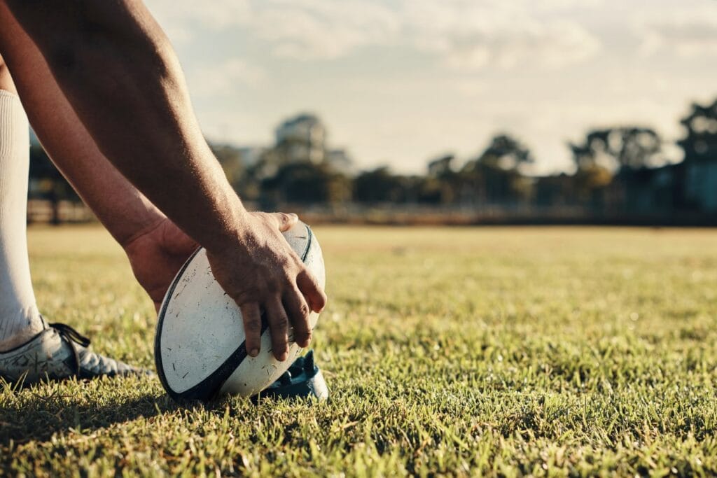 minge de rugby eco-friendly pe teren, detaliu cu jucător pregătind o lovitură, materiale sustenabile rugby