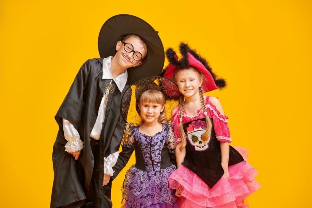 copii în costume de Halloween și serbare grădiniță, pe fundal galben, zâmbind