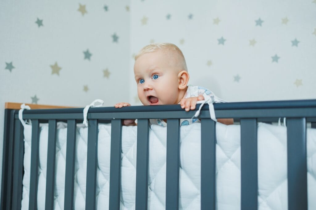 bebeluș curios la pătuț cu barieră de protecție, adaptare psihologică copil