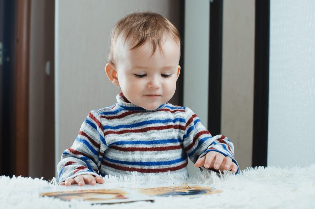 băiețel răsfoiește carte cu imagini, rolul ilustrațiilor în limbajul copiilor, carte educațională copii