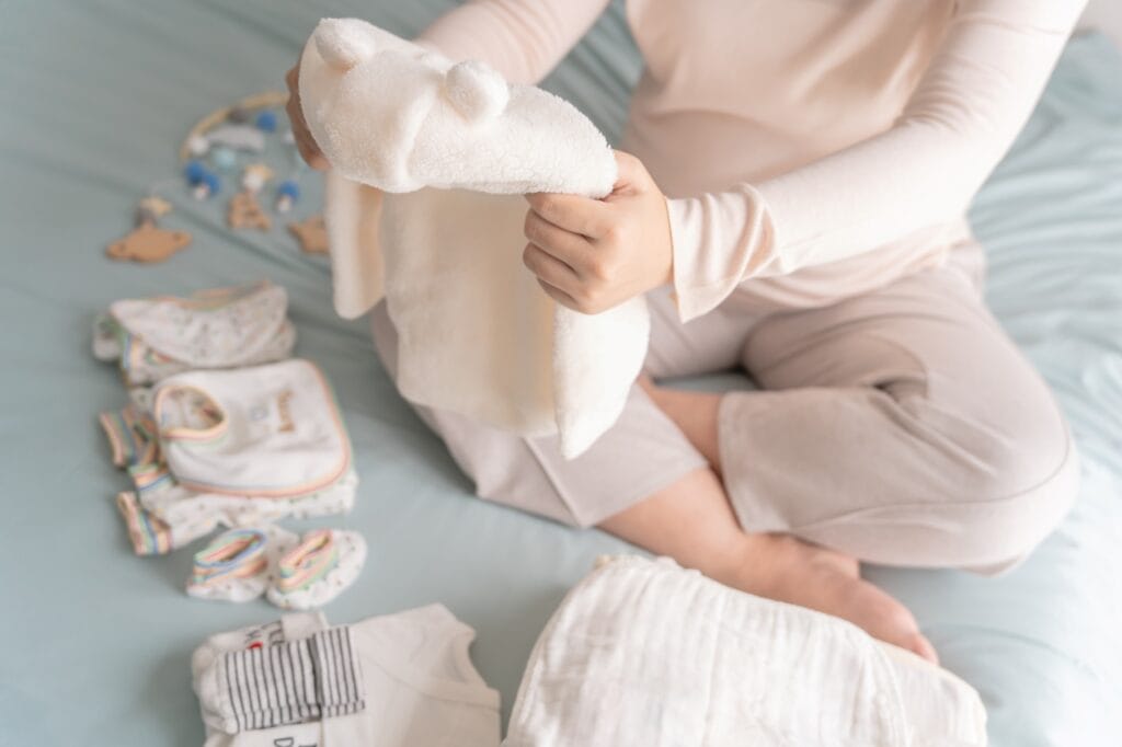 Pregătire hăinuțe sigure pentru bebeluș, cu accent pe detalii de siguranță: materiale antialergice, cusături fine și sisteme de închidere sigure