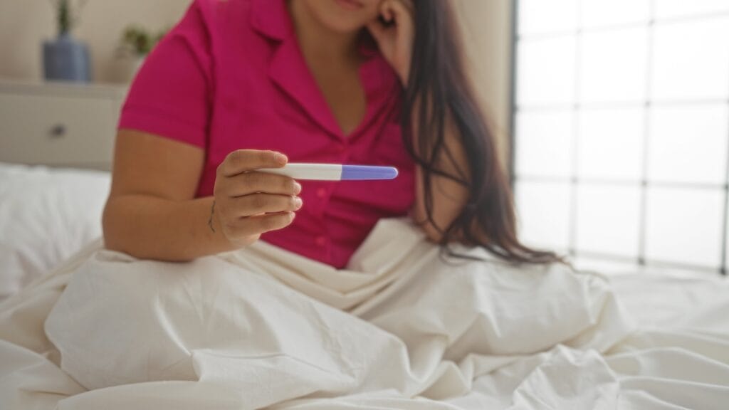 Test de sarcină cu rezultat neclar: fals pozitiv sau negativ? Imagine cu test de sarcină ținut în mână, simbolizând emoția și nedumerirea cauzate de un rezultat ambigu.